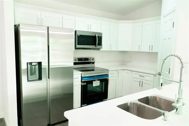 a kitchen with a sink a refrigerator and cabinets