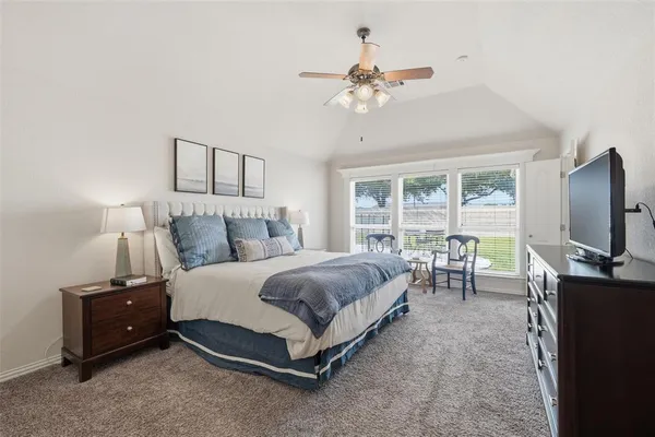 a spacious bedroom with a bed and a flat tv screen on dresser