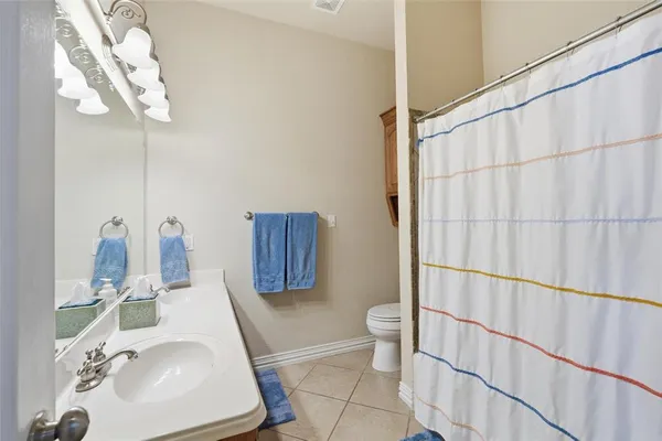 a bathroom with a sink a toilet and shower curtain
