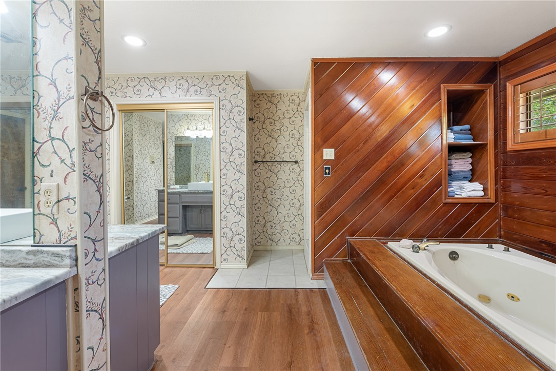 1309 Rock Dam Road Marlin, TX 76661 - Photo 27 of 50 Bathroom with a jetted tub, wood finished floors, wallpapered walls, and vanity