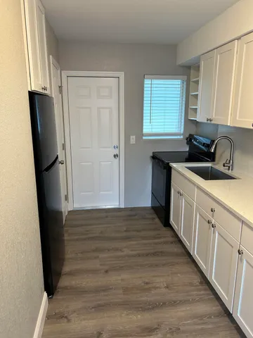 a kitchen with a refrigerator a stove a sink a window and cabinets