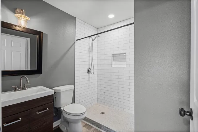 a bathroom with a granite countertop toilet a sink and a mirror