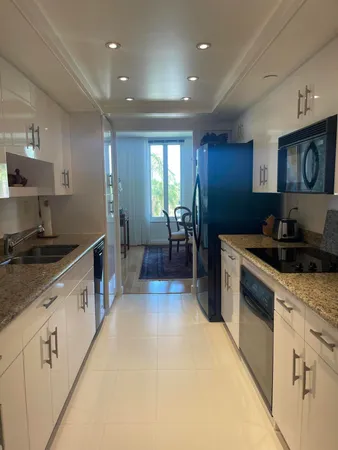 a large kitchen with stainless steel appliances a large counter top a stove a chimney a sink and a refrigerator