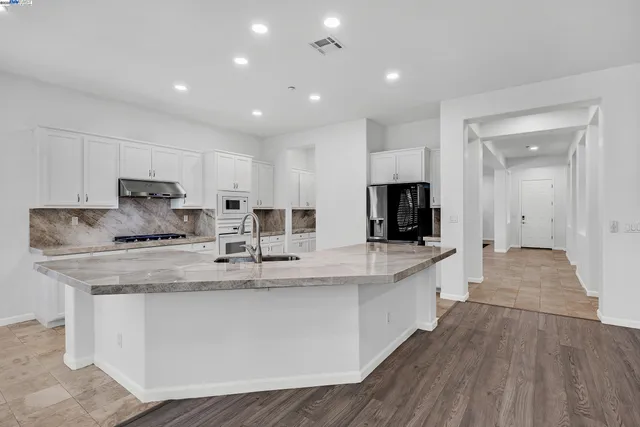 a kitchen with granite countertop a sink stainless steel appliances and white cabinets