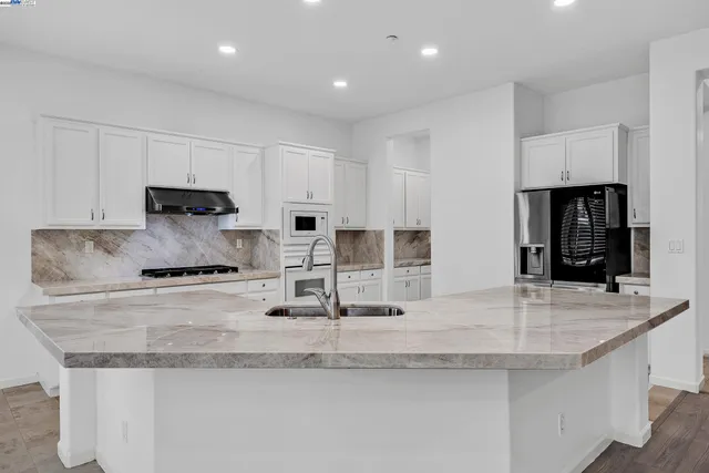 a large kitchen with stainless steel appliances granite countertop a sink stove and refrigerator