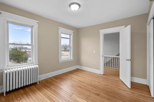 a view of an empty room with window and wooden floor