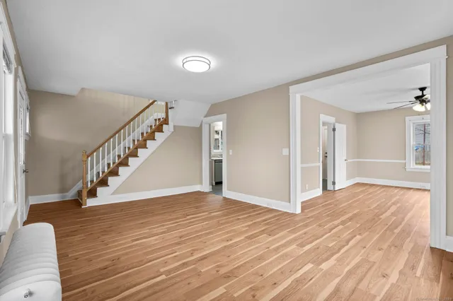 a view of empty room with wooden floor and fan