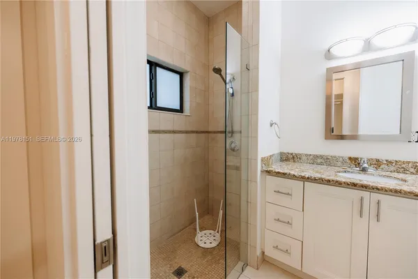 a bathroom with a granite countertop sink a mirror and a shower