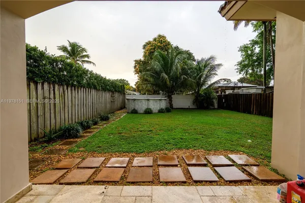 a view of a backyard with plants and wooden fence