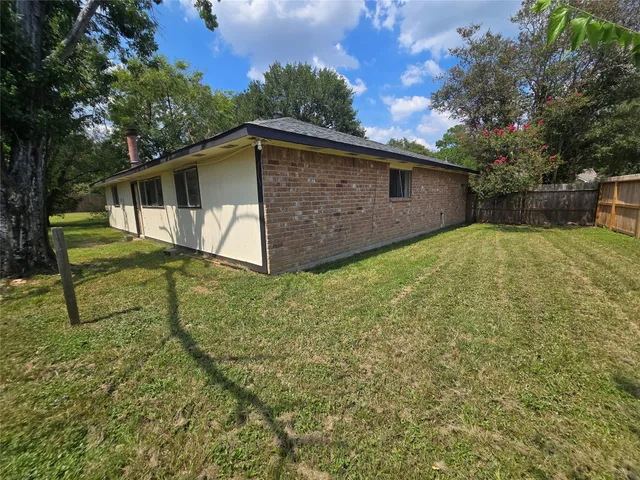 a view of backyard with wooden fence and large trees