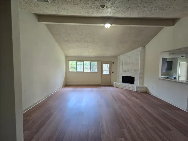 a view of empty room with wooden floor and fireplace