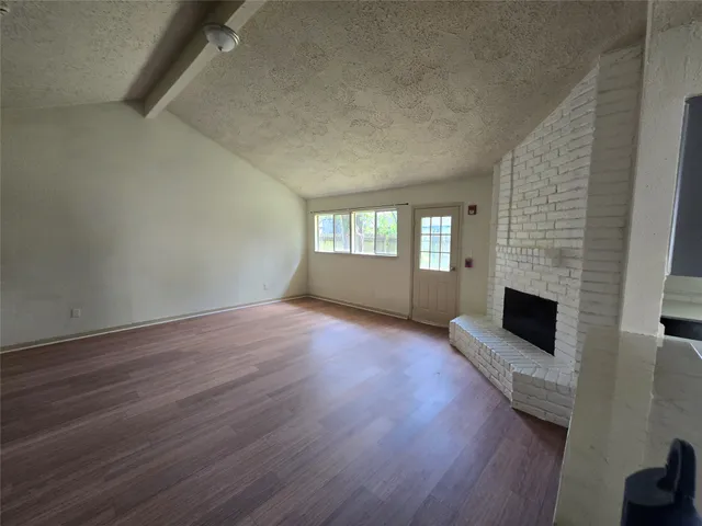 a view of empty room with fireplace and wooden floor
