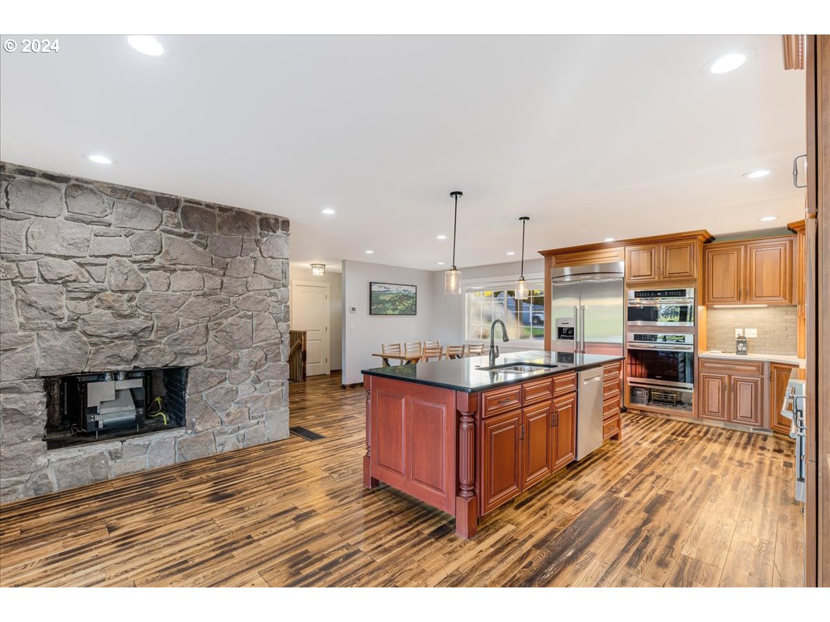 16507 Northeast 30th Court Ridgefield, WA 98642 - Photo 21 of 48 a kitchen with stainless steel appliances granite countertop a stove top oven a sink dishwasher and a fireplace with wooden floor
