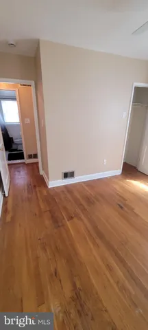 an empty room with wooden floor and mirror