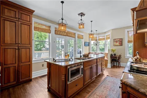a kitchen with stainless steel appliances granite countertop a stove and a view of living room
