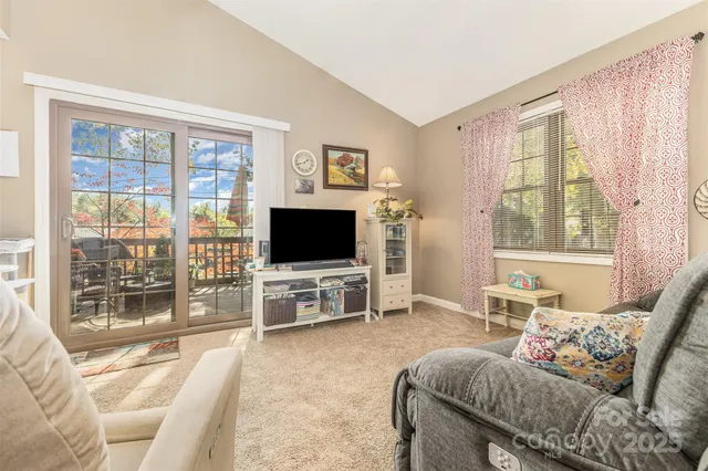 a living room with furniture a flat screen tv and a large window