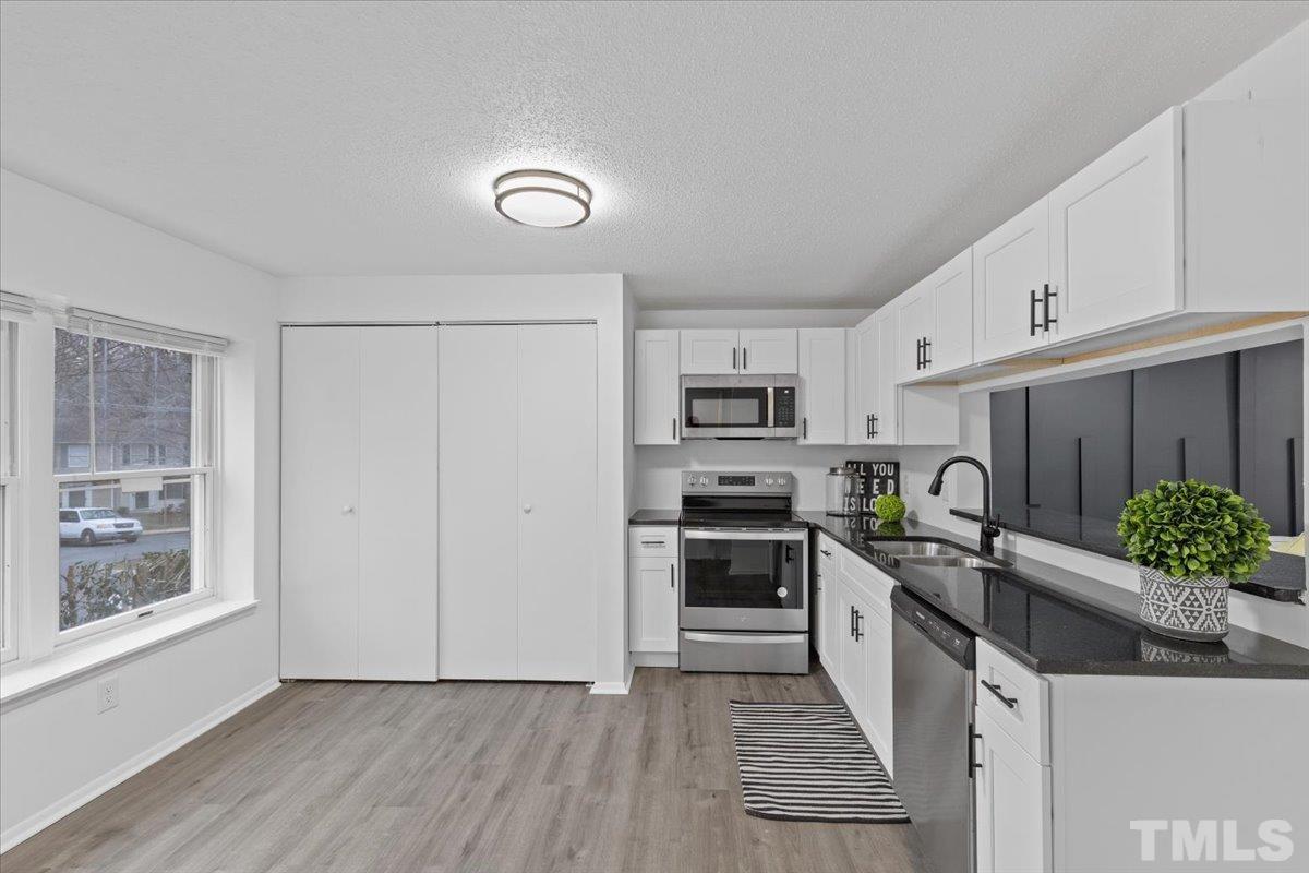 7721 Sandra Lane Raleigh, NC 27615 - Photo 5 of 29 a kitchen with stainless steel appliances kitchen island granite countertop a stove a sink and a refrigerator