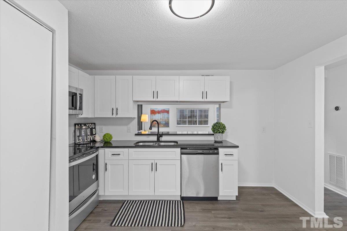 7721 Sandra Lane Raleigh, NC 27615 - Photo 7 of 29 a kitchen with stainless steel appliances granite countertop a stove a sink and a white cabinets