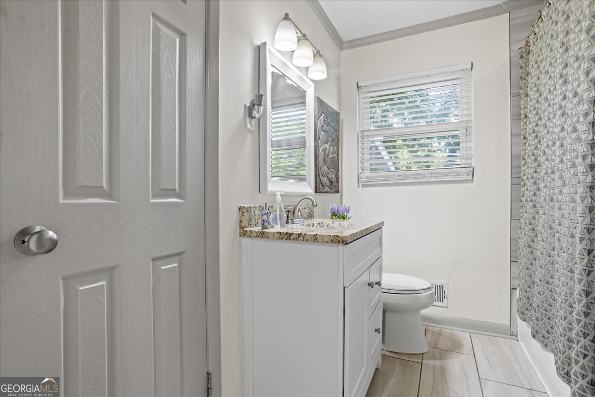 2316 Dorsey Avenue East Point, GA 30344 - Photo 23 of 25 a bathroom with a granite countertop sink toilet a mirror and shower