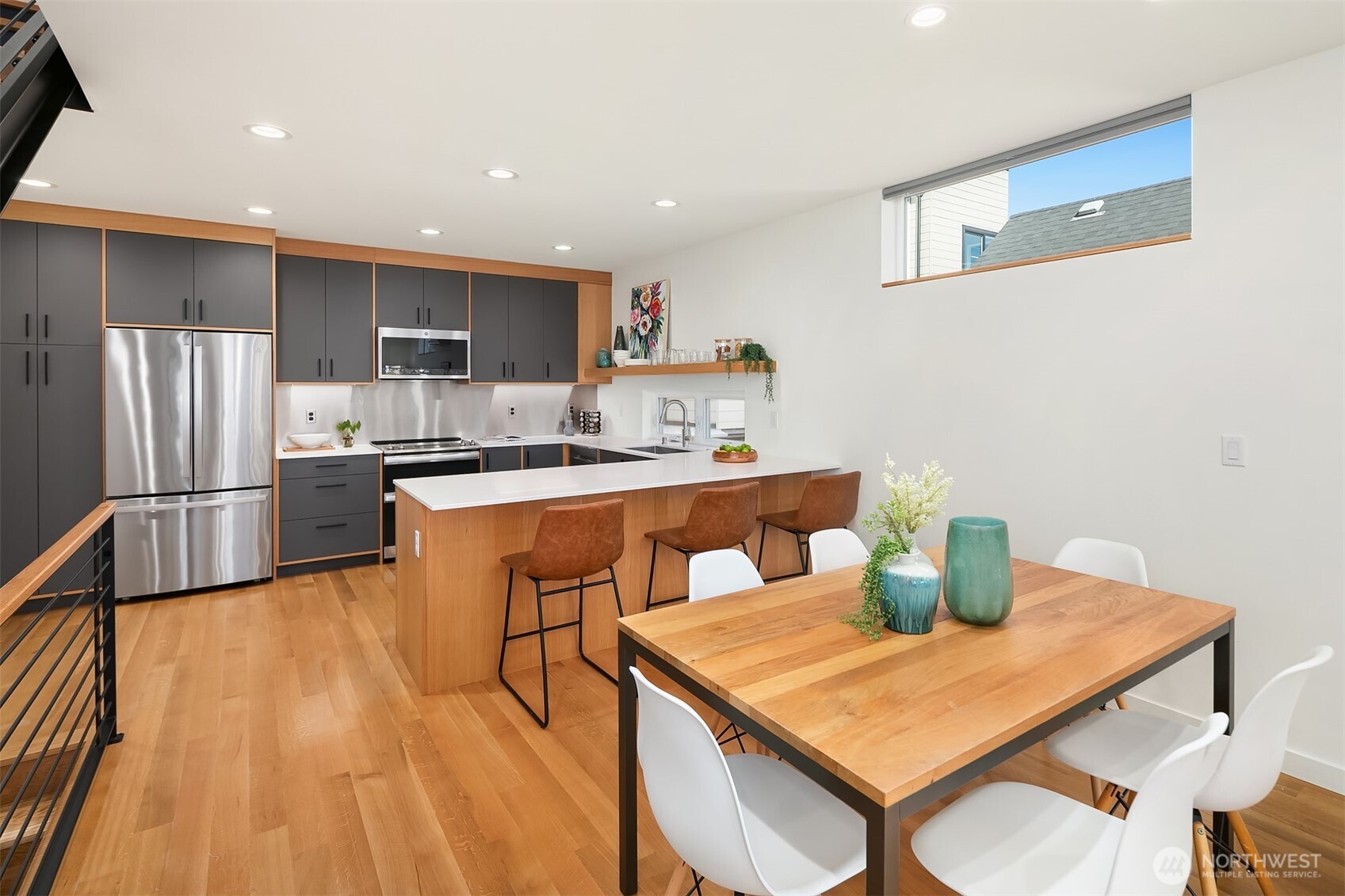 8305 12th Avenue Northwest, Unit C Seattle, WA 98117 - Photo 7 of 26 a kitchen with stainless steel appliances kitchen island granite countertop a refrigerator a stove a sink dishwasher with a dining table and chairs