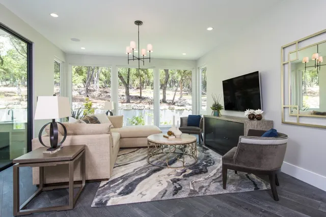 a large white kitchen with living room and stainless steel appliances