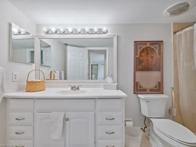 a bathroom with a granite countertop sink mirror vanity and toilet