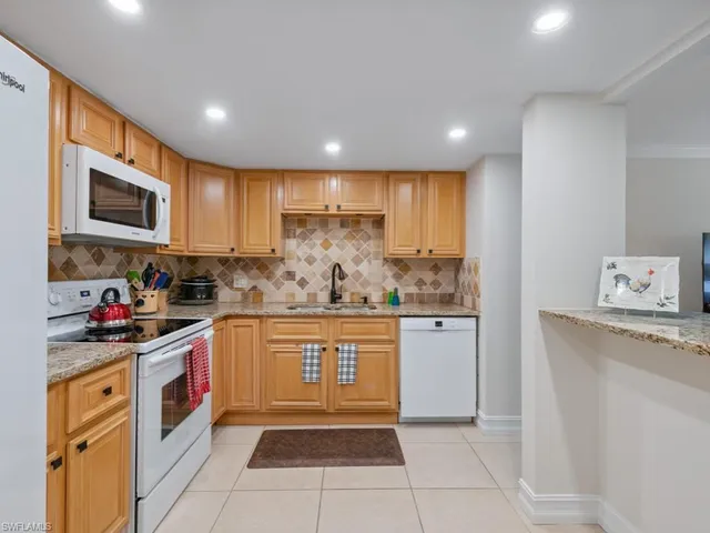 a kitchen with stainless steel appliances granite countertop a refrigerator sink stove microwave and cabinets