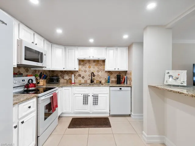 a kitchen with stainless steel appliances granite countertop a sink and dishwasher a refrigerator with white cabinets