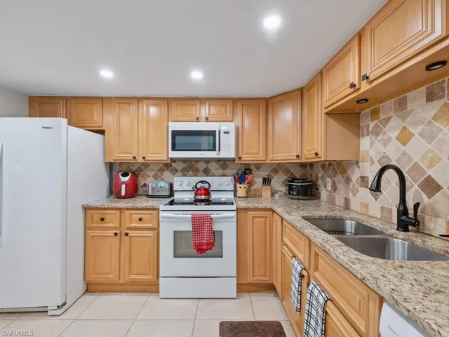 a kitchen with granite countertop white cabinets and white appliances