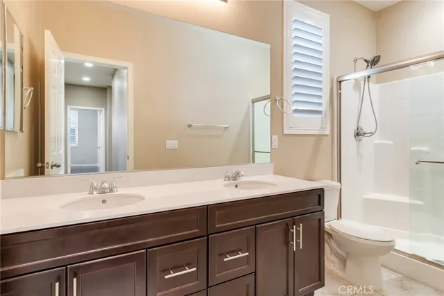 a bathroom with a sink a toilet a mirror and shower