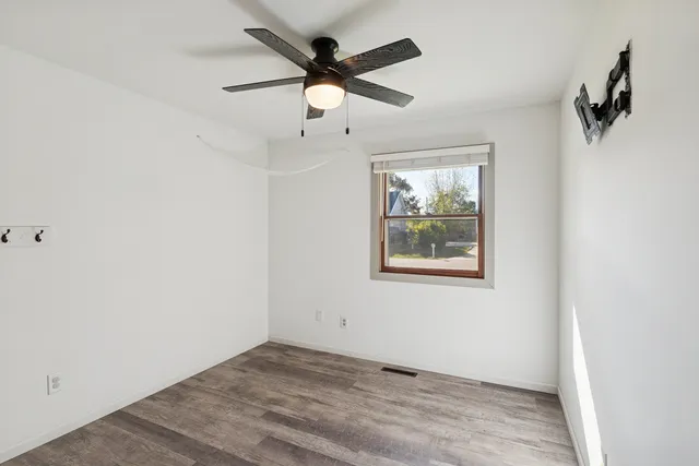 an empty room with windows and fan