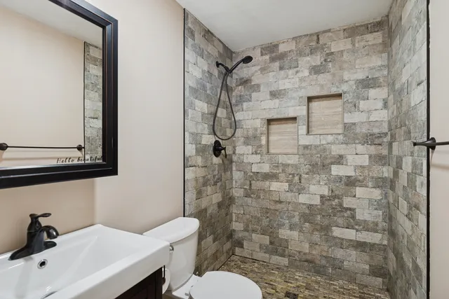 a bathroom with a granite countertop sink toilet and mirror