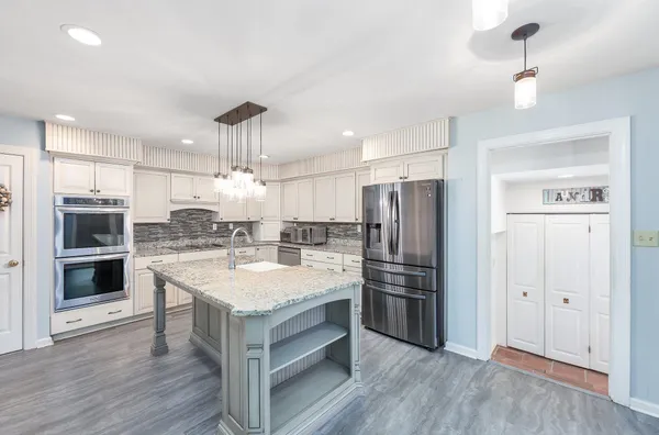 a kitchen with a center island wooden floor and stainless steel appliances