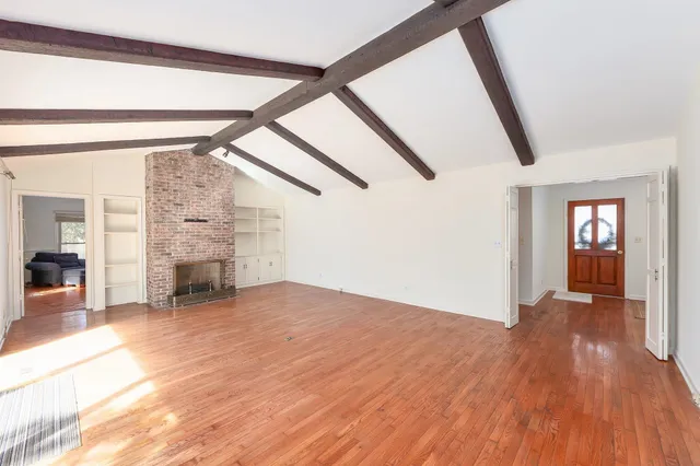 a view of empty room with stairs and wooden floor