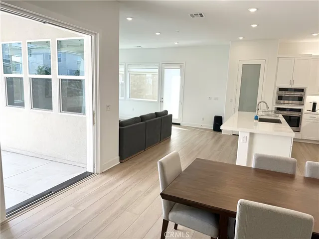 a living room with couches and kitchen view with wooden floor