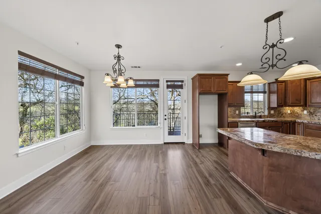 a large kitchen with stainless steel appliances granite countertop a lot of counter space and wooden floors