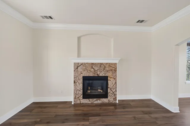 a view of an empty room with wooden floor and a fireplace