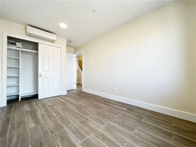 a view of an empty room with wooden floor and closet