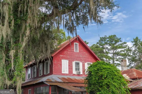a front view of a house with a garden and trees