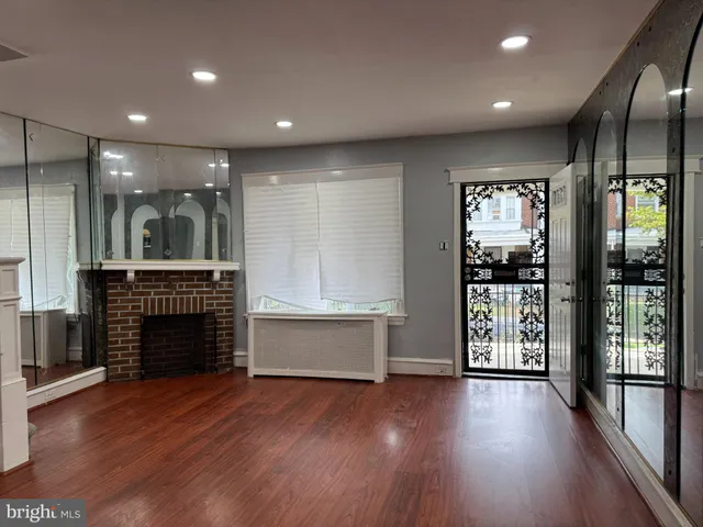 an empty room with wooden floor fireplace and windows