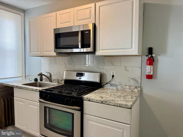 a kitchen with stainless steel appliances granite countertop white cabinets and a stove top oven