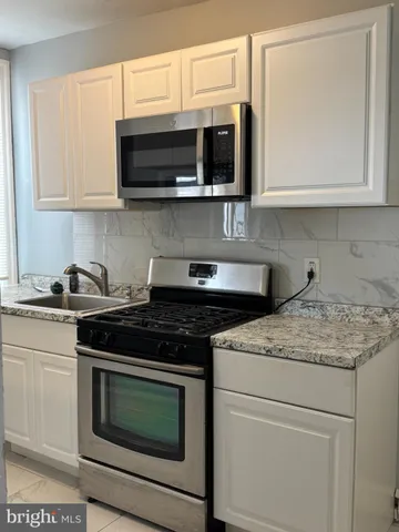 a kitchen with stainless steel appliances granite countertop stove top oven microwave and cabinets
