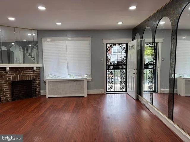 an empty room with wooden floor and a fireplace
