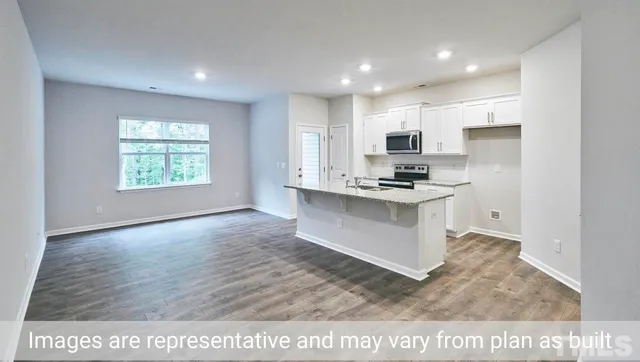 a kitchen with stainless steel appliances kitchen island granite countertop a stove a sink and a refrigerator