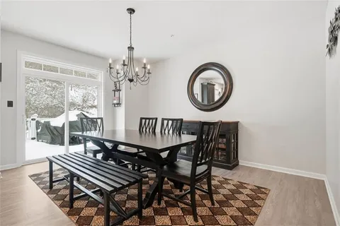 a view of a dining room and livingroom with furniture wooden floor a chandelier