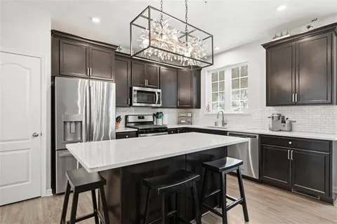 a kitchen with stainless steel appliances granite countertop a stove refrigerator and a dining table with wooden floor