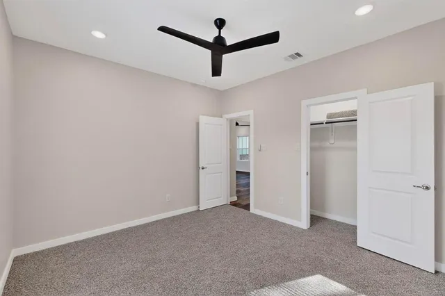 an empty room with closet and a ceiling fan