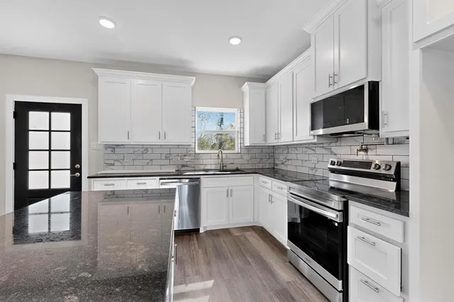 a kitchen with stainless steel appliances granite countertop a stove top oven a sink dishwasher and a microwave oven with cabinets