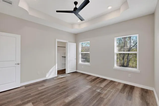 a view of empty room with wooden floor and fan