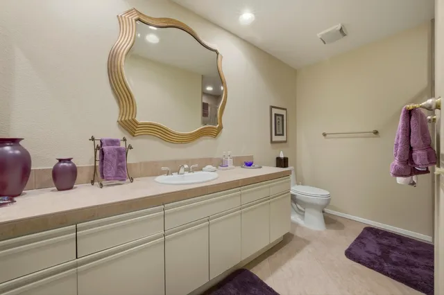 a bathroom with a toilet sink vanity and mirror